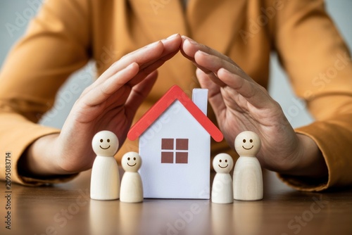 Family Protection Concept with House and Wooden Figures
