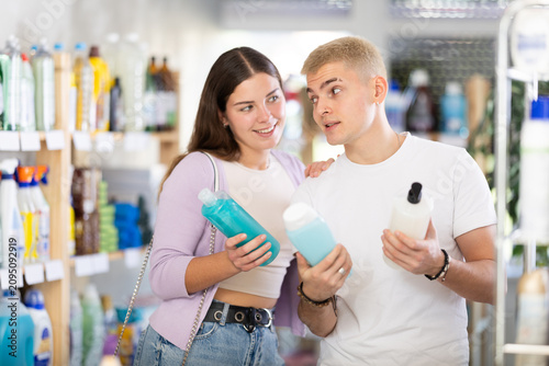 Картината върху платно Selective young couple deciding which shampoo and shower gel to buy in retail st