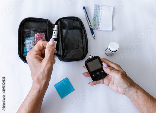 Fotografie Female hand holding a digital blood glucose meter after measuring blood sugar
