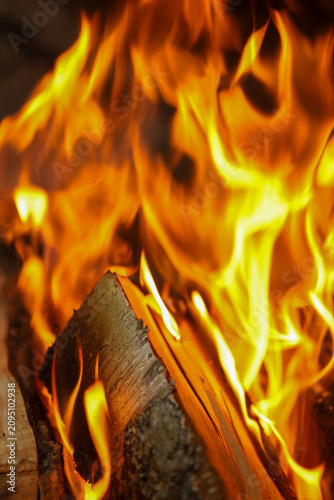 Φωτογραφία Vertical close-up shot of a vigorous fire with bright yellow and orange flames rising rapidly, consuming textured wood logs