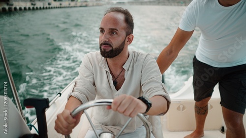 Foto Man at a boat's wheel, enjoying a summer sea outing