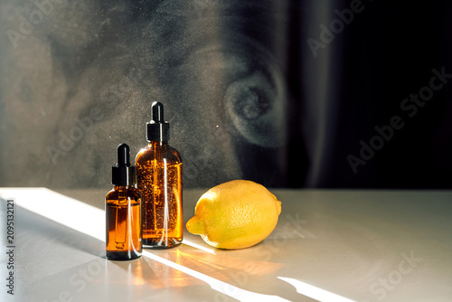 Foto Essential oil serum bottles with fresh lemon and light