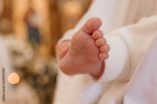 Foto Close up of newborn baby foot in white baptismal gown with soft warm bokeh lighting in a church interior