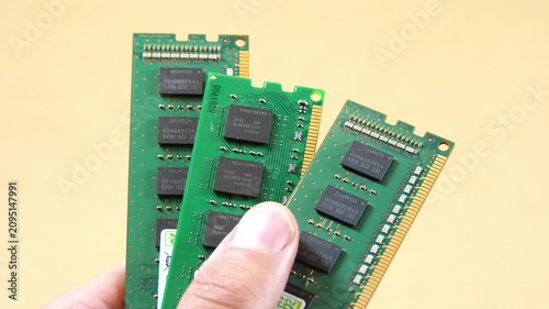 Hand fanning three green RAM memory sticks, closeup technology concept for desktop PC upgrade, component scarcity, semiconductor price increases and growing AI computing demand