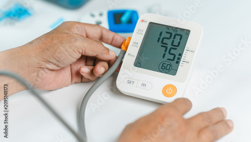 Canvastavla Close-up of a senior adult checking blood pressure with a digital monitor at home