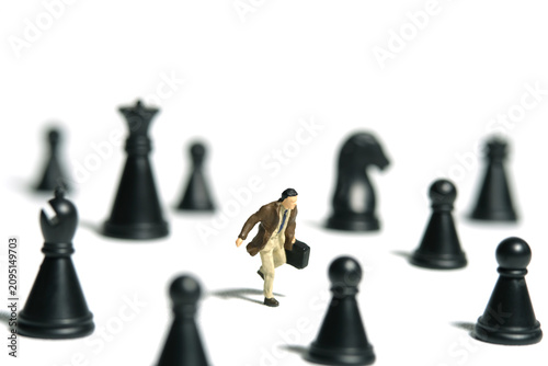 Miniature tiny people toy figure photography. A businessman running in the middle of chess pawn. Isolated on white background