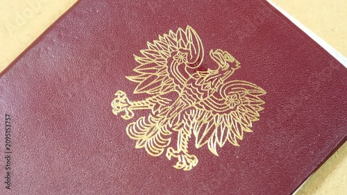 Gold uncrowned Polish eagle emblem on a burgundy official document cover, archival closeup of the communist-era Polish People's Republic coat of arms, national identity, politics, history and heritage