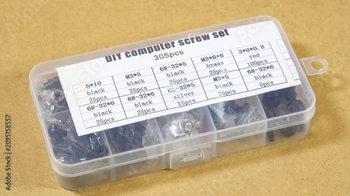 Transparent 305-piece DIY computer screw assortment box with labeled compartments, close-up panning video of black, silver, brass and red fasteners for electronics repair, upgrades and right to repair