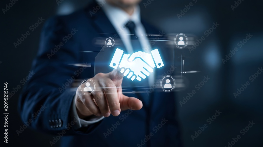 Obraz premium Businessman touching a holographic handshake icon on a digital screen to symbolize business partnership and professional agreement