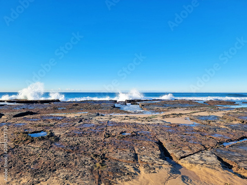 Waves crashing on the rock platform at Susan Gilmore Beach Newcastle New South Wales Australia. Taken at low tide