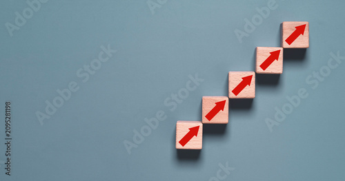 Photography Wooden blocks with upward arrows arranged as ascending steps symbolize business growth, career advancement, success strategy, goal achievement, continuous improvement, progress and development