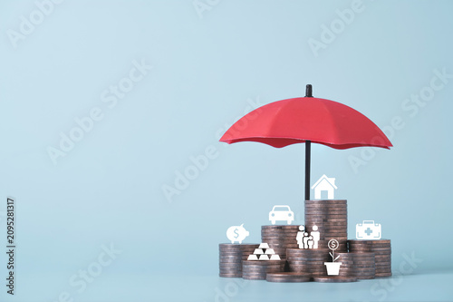 Red umbrella protecting stacks of coins with financial icons represents insurance coverage, wealth protection, financial security, risk management, investment planning and long term asset protection.