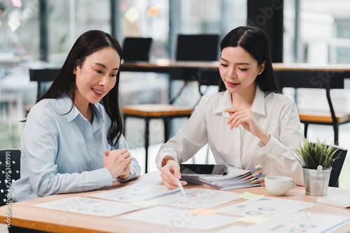 Two asian professional women working together with business financial documents in modern office