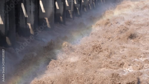 A slow-motion close-up of powerful floodwater discharging from a dam spillway