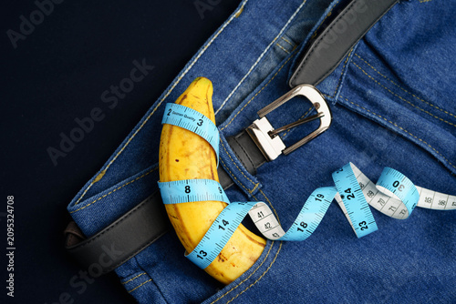 Bild auf Leinwand Banana with measuring tape on jean trousers, penis health.