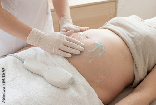 Obstetrician Performing Abdominal Ultrasound Scan On Expectant Mother In Clinic