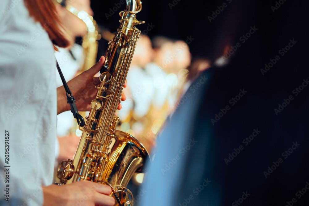 Obraz premium Female Saxophonist Holding Shiny Instrument Close Up Profile View. Young woman in white uniform shirt holds brass saxophone during musical band performance 