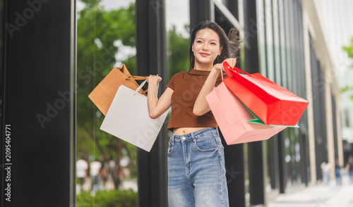 Bild auf Leinwand Smiling asian woman walking and holding shopping bags, Fashion shopping, retail