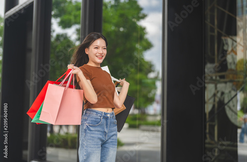 Asian happy woman holding shopping bags celebrating beauty shopping and flash sale, Smiling female customer enjoying seasonal sale promotion, Modern retail consumer and customer satisfaction concept