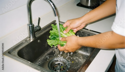 Fresh Greens Being Washed in Kitchen Sink with Running Water