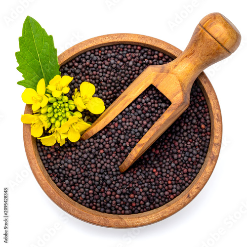 Top view of wooden bowl of black mustard seed with flower on white bacground