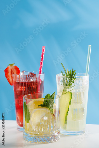 Assortment of non alcoholic refreshing drinks with herbs and citrus on blue background