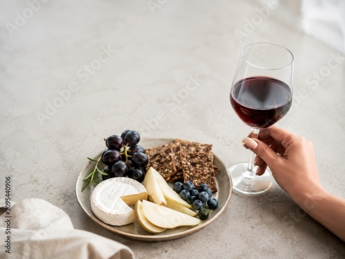 Comer queso, fruta y galletas con una copa de vino en una mesa