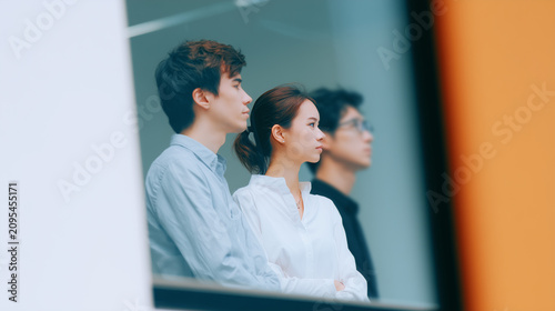 Young adult office window glass business team people colleague corporate bright young adult colleague standing behind glass modern office, thoughtful expression, teamwork atmosphere, blurred