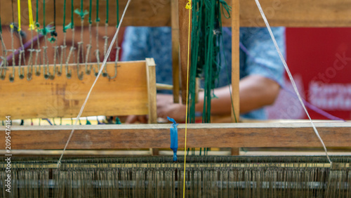 A textile artisan is weaving a piece of fabric, a traditional Indonesian textile.