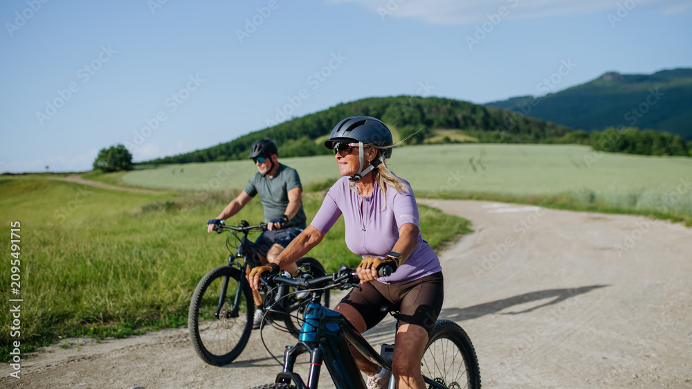 Fototapeta premium Active senior couple exploring nature on electric bicycles