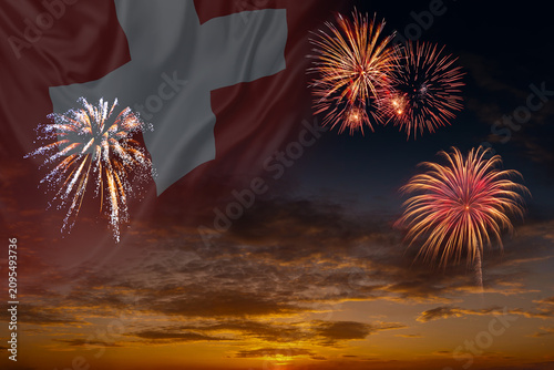 Waving National flag of Switzerland and holiday fireworks on evening sky