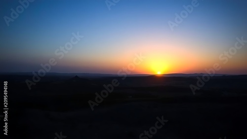 Golden rays of dawn breaking over the horizon into a deep blue pre-dawn sky.