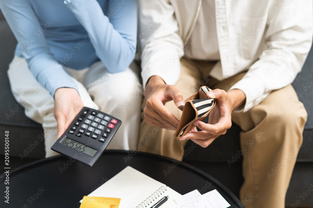 Fototapeta premium Stressed financial owe asian young couple love sit suffer, stressed and confused by calculate expense from credit card at home, no money to pay, mortgage or loan. Debt, bankrupt or bankruptcy people.