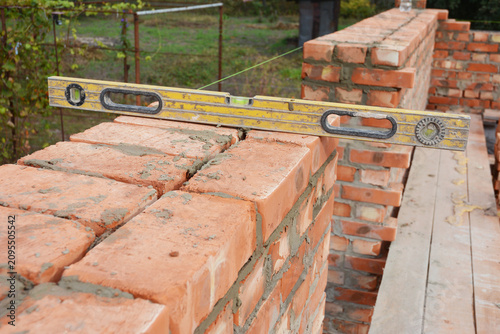 Construction brick wall building with masonry work and spirit level tool