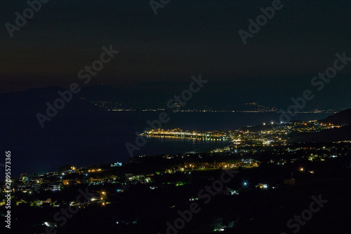 Foto Coastal city lights reflecting on calm sea at night