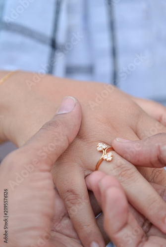Obraz na płótnie Close-up of a man placing a delicate floral engagement ring on a woman's finger,