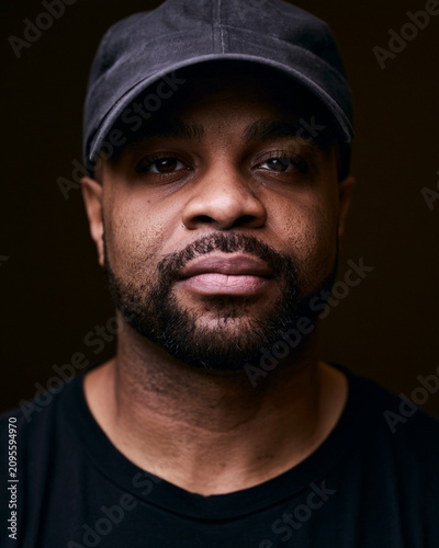 Close Up Portrait of Smiling Black Man Wearing Baseball Cap and Black T Shirt