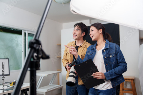 Asian creative directors planning photoshoot with camera and clipboard in studio