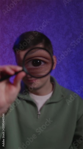 Funny guy laughing while looking through magnifying glass at camera