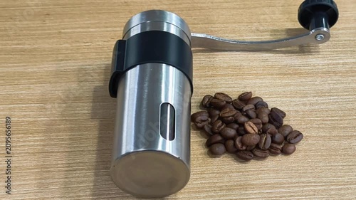 Manual Stainless Steel Coffee Grinder with Roasted Coffee Beans on Wooden Table