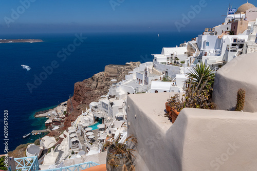 Fotografie Traditional white architecture cascading down a volcanic cliff in Oia, Santorini