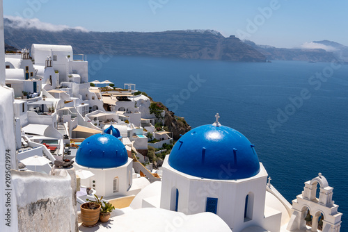 Bild auf Leinwand Famous white churches with blue domes and tiered bell tower in Oia, Santorini