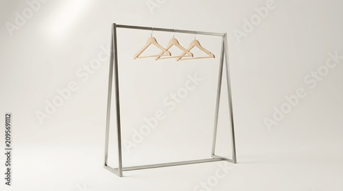 Minimalist silver metal clothing rack with three wooden hangers in a bright studio