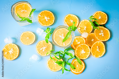 Fényképezés Lemon water glasses with fresh lemon slices, mint and ice on a blue background,
