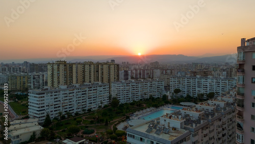 Mersin, Turkey. Sunset panorama over residential district with apartment buildings. Sun descending behind mountains in haze, Mezitli urban landscape at golden hour.. Aerial View
