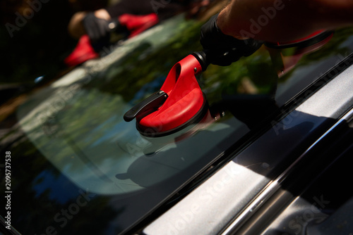 Detailed close-up of a vacuum grip seating auto glass onto automotive sealant during an outdoor windshield replacement process