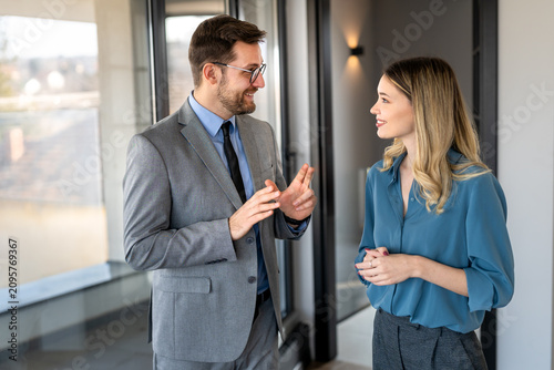Two happy diverse multiethnic business team people working, talking in corporate office