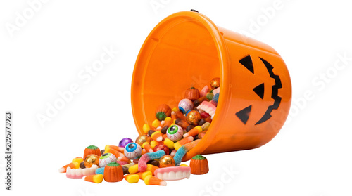 Orange halloween pumpkin bucket spilling colorful candy, gummy worms and eyeball sweets isolated on white or transparent background.