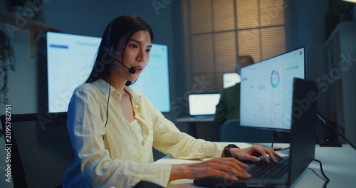 Team young Asian businesswoman working late talk on telephone headset in call center office at night. Corporate customer service support, telemarketing, finance insurance investment advisor concept.