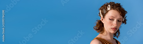 Принти на полотні Young woman with red curly hair exudes elegance in stylish attire against a vibr